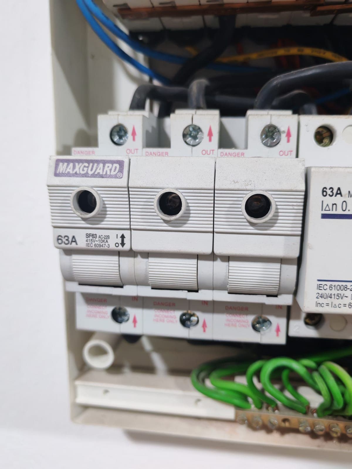 Close-up of an existing three-phase distribution board and protective devices during inspection.